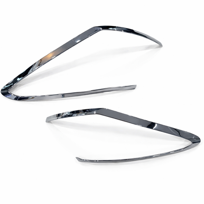 Two chrome car headlight covers on a white background