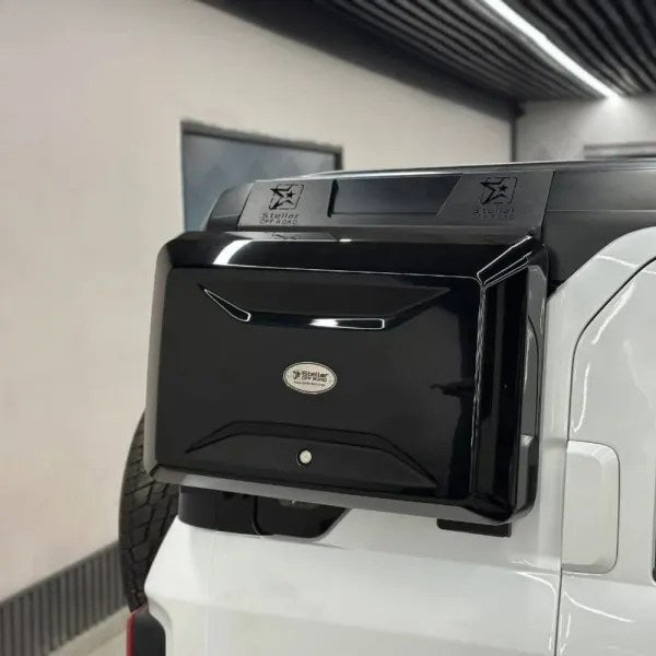 Black vehicle storage box attached to a white truck in a garage.