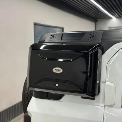 Black vehicle storage box attached to a white truck in a garage.
