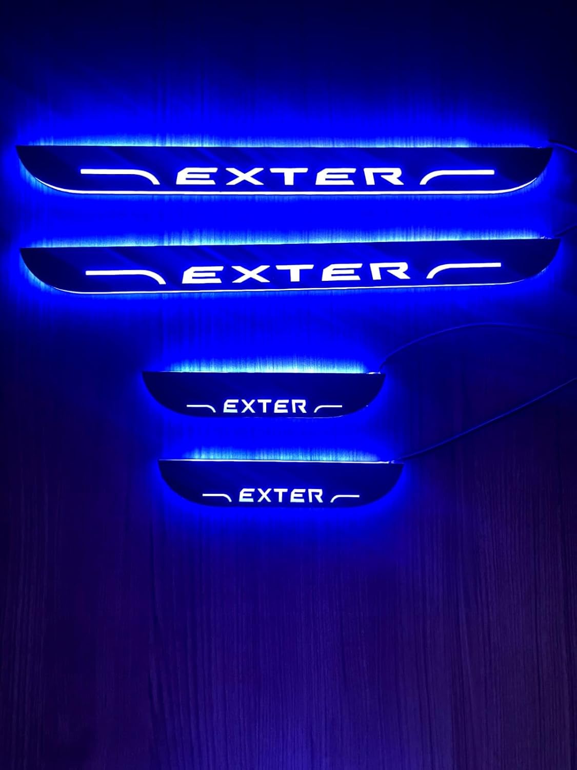 Set of illuminated car door sills with 'EXTER' branding on a dark background
