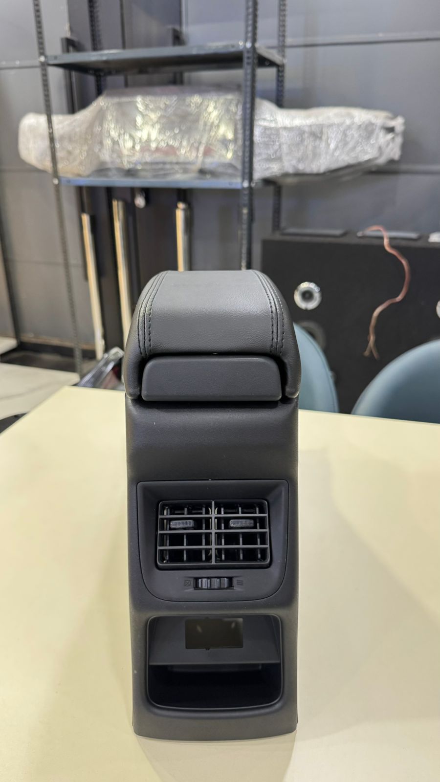 Car seat armrest with cup holder and air vent on a table